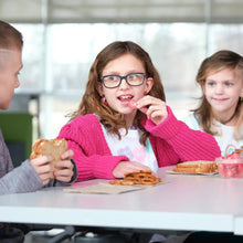 Children eating snacks at a table with bowls of cereal-like topping