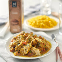 Braised pork with herb seasoning in a white dish, with spice bottle in view