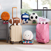 Assorted plush sports toys with faces, displayed on luggage and books in a room