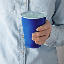 Dark blue plastic party cup held by hand with ice inside