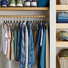 Closet rod with multiple rubberized hangers, black frames hanging shirts and jeans