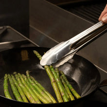 Heavy duty utility tongs holding asparagus spears in a pan, silver