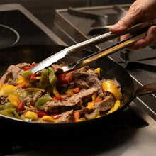 Heavy duty utility tongs lifting food from a frying pan, silver