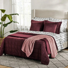 Herringbone velvet plush blanket in burgundy, layered over bed with quilted edge detail