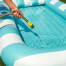 Inflatable sun tub with blue-striped edge, blue basin being filled with hose