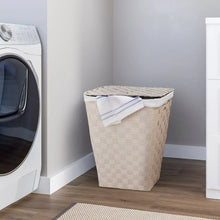 Woven laundry hamper with white liner and folded cloth on top, light cream.