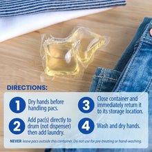 Yellow laundry detergent pac in clear plastic wrap, beside folded denim jeans.