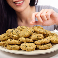 Lemon blueberry cookie thins on a plate, with a hand reaching toward cookies
