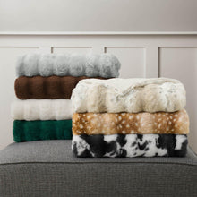 Faux fur throw blanket stack with cream, gray, green, brown, and black-and-white layers.