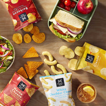 Assorted chips and crackers with sandwiches on a tray