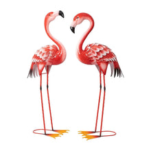 Pair of red metal flamingo statues with feather-texture wings and black beaks, standing on bases