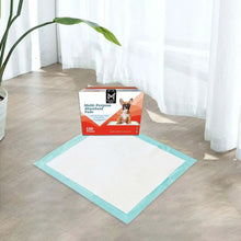 Teal-bordered absorbent pad on floor with product box behind