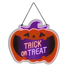 Neon pumpkin wall sign “Trick or Treat” in purple glow on an orange frame