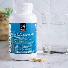 Organic Ashwagandha dietary supplement bottle with loose capsules and nearby glass