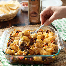 Organic ground cumin jar beside spoon over baked casserole dish