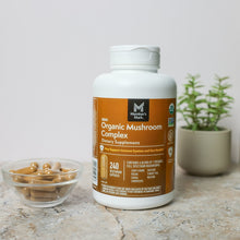 Organic mushroom complex supplement bottle with capsules in glass bowl