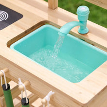 Wooden mud kitchen faucet pouring into turquoise sink basin