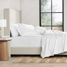 White solid sheet set on bed with pillowcases and neatly draped blanket