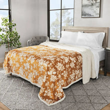 Plush blanket with orange floral print draped over bed