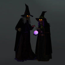 Two dark witch figurines with glowing eyes and purple-lit crystal ball