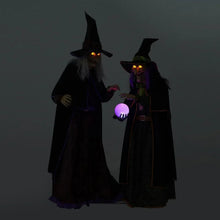 Pair of witch figures with glowing eyes and a purple lit crystal ball between them