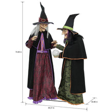 Two witch figurines standing together, one in maroon patterned dress, one in green