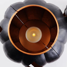 Interior view of black metal jack-o-lantern showing glowing candle and orange rim
