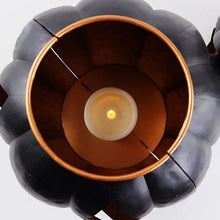 Black metal jack-o-lantern top with central candle holder and small glowing light