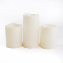 Three white pillar candles with warm light, pre-lit candle set