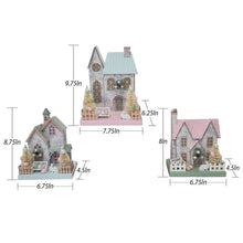 Three pre-lit paper houses with pastel roofs, snowy speckled walls, and decorative trees
