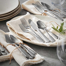 Stainless steel flatware set with forks, spoons, and knives on folded cloth