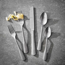 Stainless steel fork, spoon, and knife arranged on gray surface