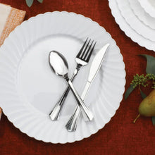 Silver-look plastic cutlery set with spoon, fork, and knife on a white plate
