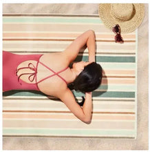 Striped beach towel laid flat, pastel pink and white with thin coral accent lines