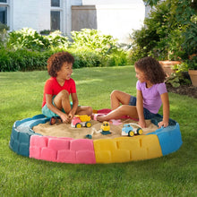 Children's inflatable sandbox with blue, pink and yellow padded border, sand interior.