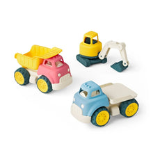 Toy trucks and construction vehicles for sandbox play in yellow, pink, and blue.