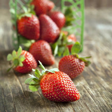 Red strawberries with green leaves on a weathered wooden table