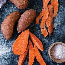 Sweet potatoes and slices with a hand holding pieces, plus salt bowl