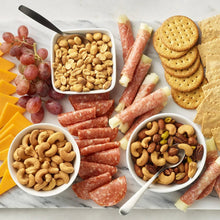 Assorted snack platter with cashews, crackers, and sliced sausage