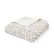 Cozy throw blanket, folded white fabric with dark geometric dot pattern