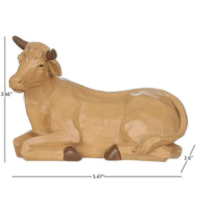 Wooden nativity ox figurine with tan finish and curled horns, lying on side