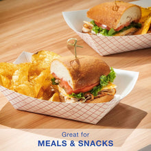 Paper food tray with red grid liner holding a deli sandwich and chips.