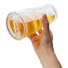 Ribbed glass cup with lid and straw, amber beverage in textured sides