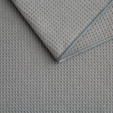 Gray microfiber kitchen towel with waffle texture and stitched edge, folded corner.