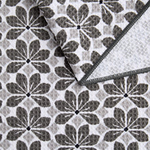 Floral printed microfiber kitchen towel in white with dark leaves, gray stitched border.