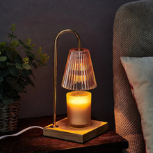 Electric candle warmer lamp with ribbed glass shade, gold frame, glowing candle on wood base