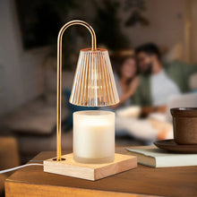 Electric candle warmer lamp with gold arch and ribbed glass shade over glowing candle on wood base