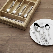 Stainless steel flatware on white plate with wood drawer caddy, assorted pieces