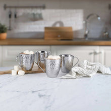 Set of 4 hammered stainless steel mugs with curved handles on a counter