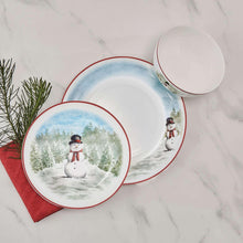 Snowman dinnerware place setting with overlapping plates and a bowl featuring red rim and trees
